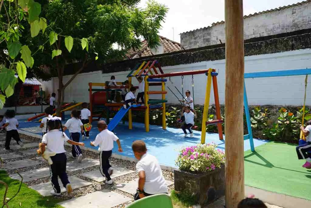 Niñas y niños corriendo hacia el parque infantil